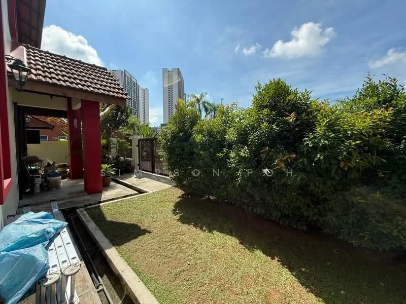 Exterior type: detached bungalow; features: manicured lawn, mature shrubs, paved walkway, red tiled roof, fenced garden, surrounded by high-rise buildings, clear blue sky; style: tropical-modern.