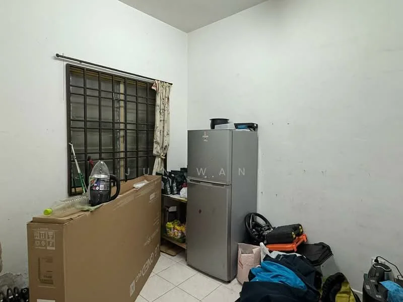 Room features: white painted walls, tile flooring, single-door fridge, cardboard box, vacuum cleaner, various bags, window with metal grille, curtains.