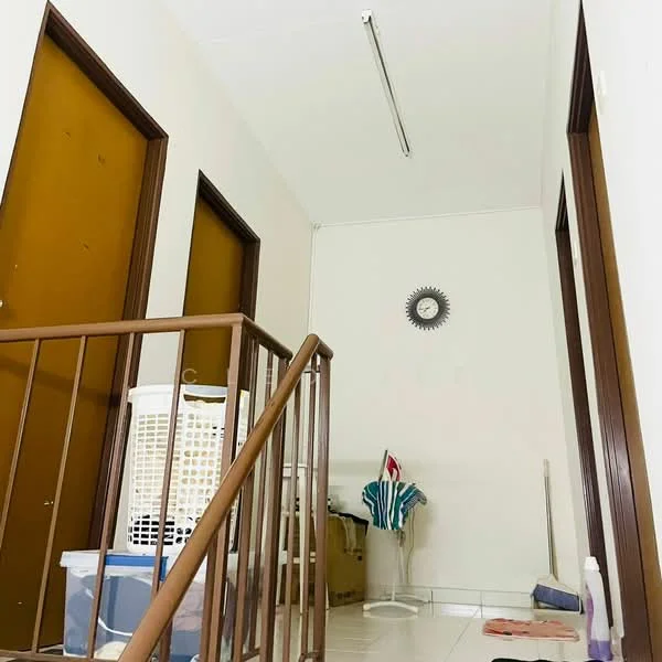 Hallway features: white painted walls, tile flooring, wooden handrail, two wooden doors, clock on wall, laundry basket, cleaning supplies, doormat.