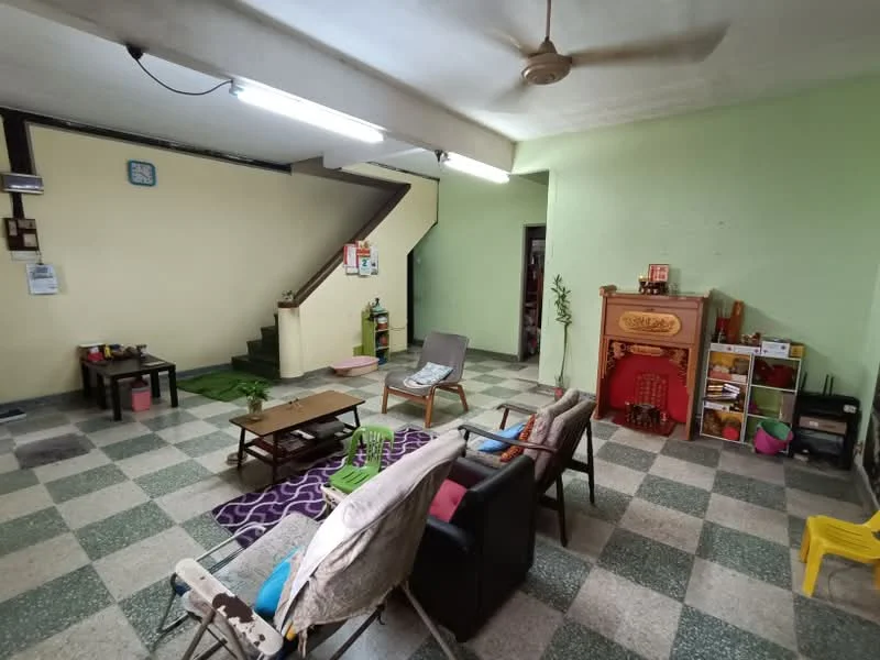 Living features: green painted walls, grey and white checkered tile flooring, ceiling fan, recessed fluorescent lighting, wooden staircase, wooden coffee table, 2-seater black leather sofa, 3-seater fabric sofa in beige, area rug with geometric pattern, decorative shelf unit, houseplants in ceramic pots, wall clock.