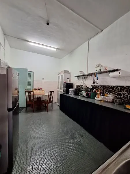 Kitchen features: black countertop, white cabinetry, stainless-steel fridge, built-in kitchen cabinets, black tile flooring, wall-mounted shelves, kitchen sink, kitchen appliances, dining table with chairs, overhead fluorescent lighting.