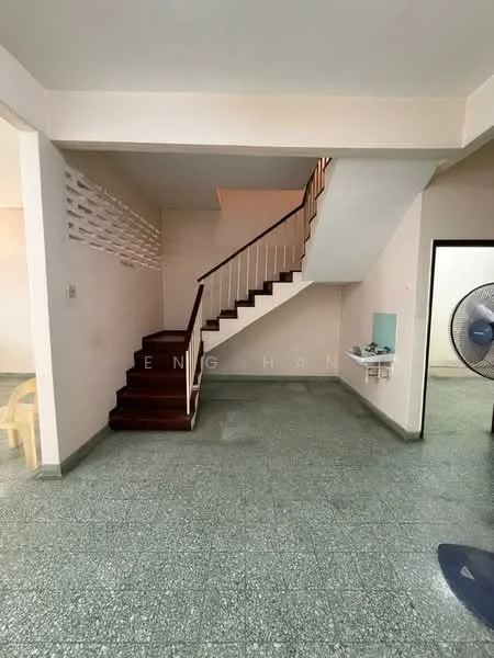 Room features: green terrazzo flooring, white painted walls, staircase with wooden steps and white railing, wall-mounted fan, open space layout, natural light from windows, corner for potential furniture placement, no visible decor; style: minimalist.