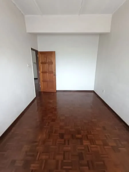 Room features: wooden flooring, white painted walls, single wooden door, no visible windows, high ceiling, empty space.