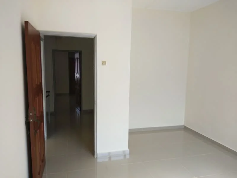 Room features: light beige painted walls, glossy grey tile flooring, wooden door, door frame, plain ceiling, no visible windows, empty room; style: minimalist.