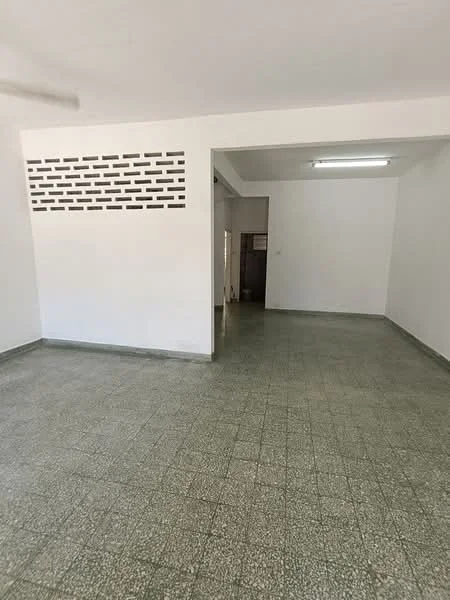 Room features: white painted walls, green speckled tile flooring, fluorescent ceiling light, open layout, decorative brick wall feature, no visible furniture, large empty space, neutral color scheme; style: minimalist.