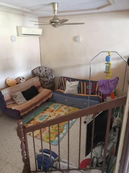 Living features: 2-seater fabric sofa in beige, 3-seater fabric sofa in pink, colorful area rug with cartoon pattern, wall-mounted TV, 1 wall-mounted split AC, ceiling fan, decorative wall sconce, staircase railing, light-colored painted walls, tile flooring.