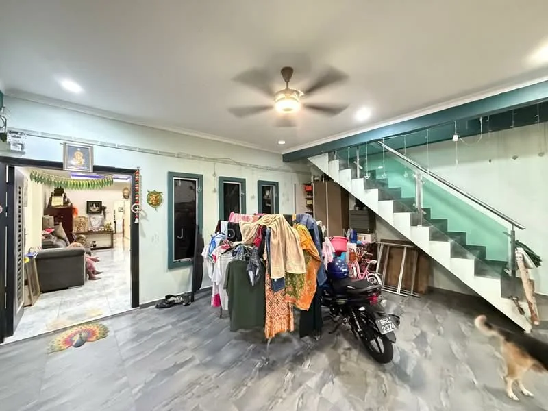Living features: grey tiled flooring, white painted walls, 5-blade ceiling fan with light, staircase with glass railing, sofa in dark color, decorative wall art, clothes drying rack with various clothes, motorbike parked, open layout, natural light from windows; style: modern.