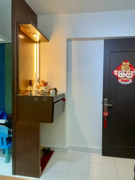 Room features: white walls, glossy white floor tiles, wooden console with built-in lighting, decorative items on console, dark wood door, red decorative wall hanging, small red tassel decoration, corner of a blue wall visible; style: modern.