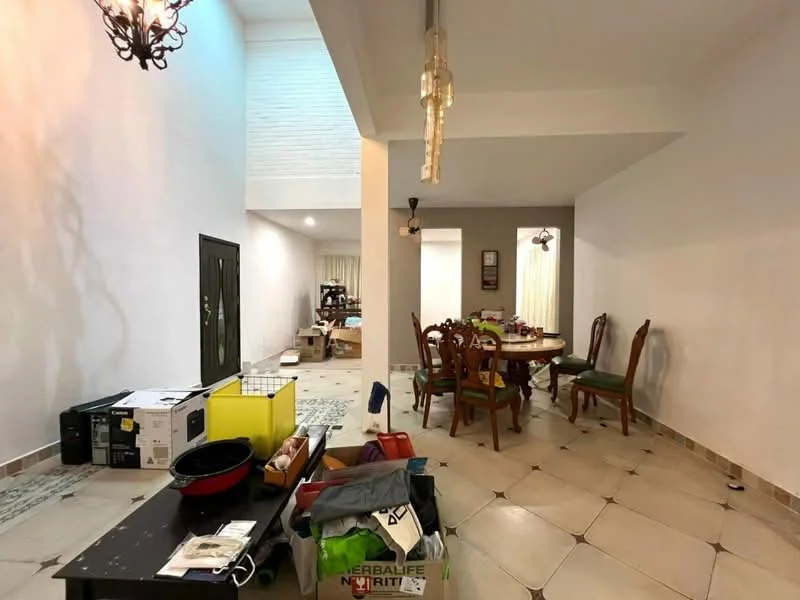 Living features: white painted walls, tile flooring, chandelier, recessed lighting, dining table with chairs, decorative wall clock, open layout, various boxes and items scattered, green area rug.