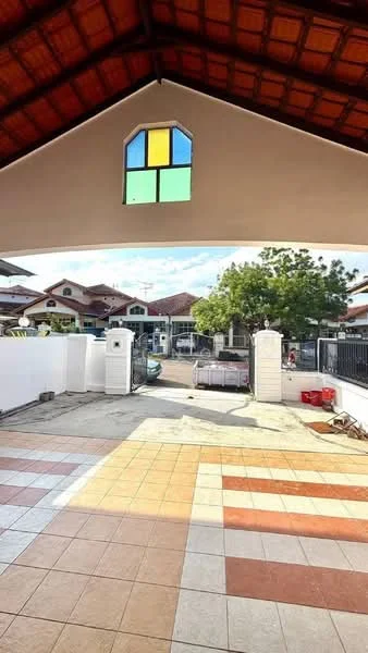 Exterior type: detached bungalow; features: arched window with colored glass, high-pitched roof with wooden beams, paved driveway with alternating tile colors, manicured landscaping with trees, white perimeter wall, gate entrance, visible neighboring houses, open outdoor space; style: modern.