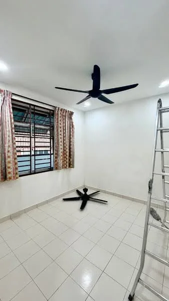 Room features: white painted walls, ceiling fan with 5 blades, tiled flooring, window with black metal grille, curtains with floral pattern, ladder, corner of the room, light fixtures on ceiling.
