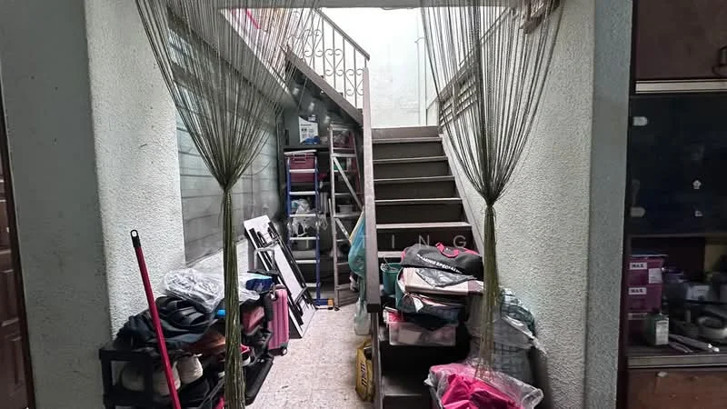 Room features: staircase with railing, concrete flooring, walls with light grey paint, storage shelves, various boxes and items stored, hanging netting, natural light from upper level, open space leading to stairs.