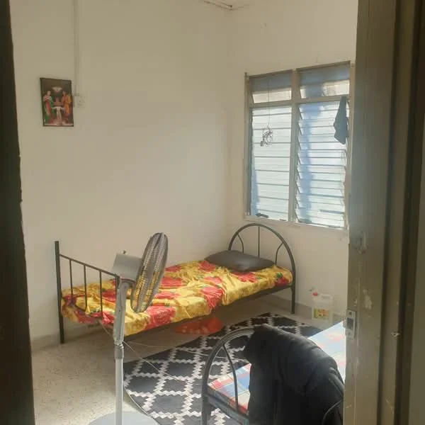 Bedroom features: single bed with floral bedding, black metal bed frame, window with horizontal slats, ceiling fan, area rug with geometric pattern, wall-mounted artwork, light-colored walls, tile flooring.
