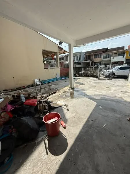 Exterior features: concrete flooring, partially covered area, fenced boundary, visible vehicle, debris and construction materials, exposed walls, sunlight casting shadows.