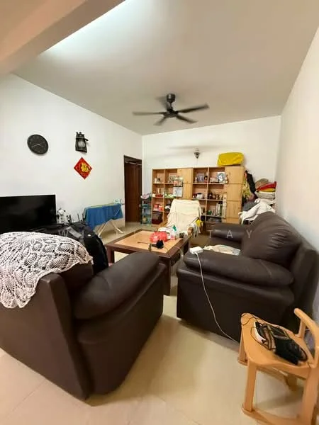 Living features: 2 brown leather sofas, wooden coffee table, ceiling fan, wall-mounted TV, wooden shelving unit with various items, cream painted walls, tile flooring, decorative wall clock, blue tablecloth on a side table, electrical cords visible.