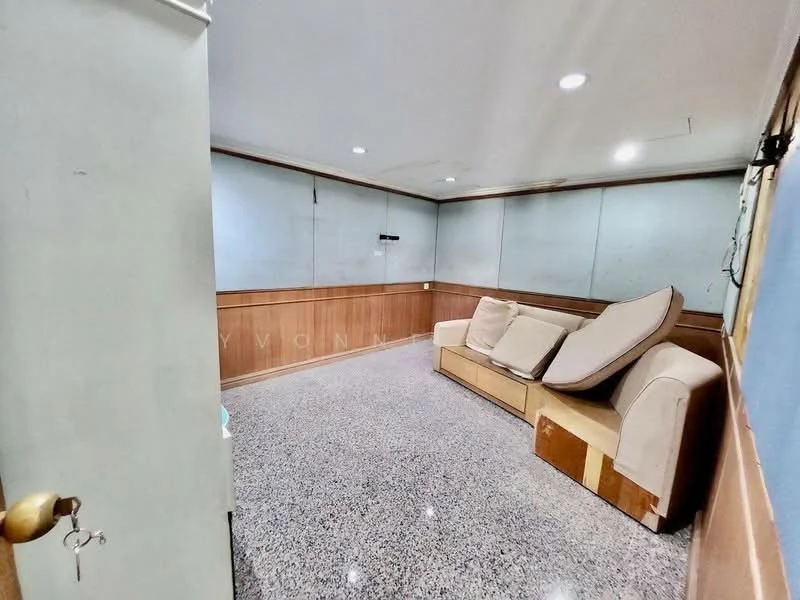 Room features: grey granite flooring, wood paneling on lower walls, white painted walls, sofa with beige upholstery, wall-mounted TV bracket, recessed ceiling lights, door with wooden finish, corner with visible wall, empty space with no visible decor; style: modern.