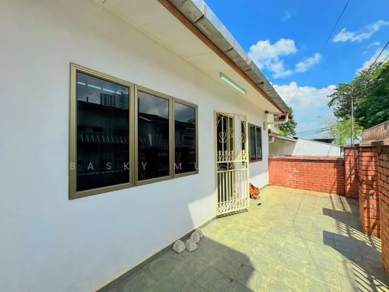 Exterior features: white painted facade, brick wall, slate tile flooring, metal security gate, large windows with gold frames, outdoor space, clear blue sky, surrounding greenery; style: modern.