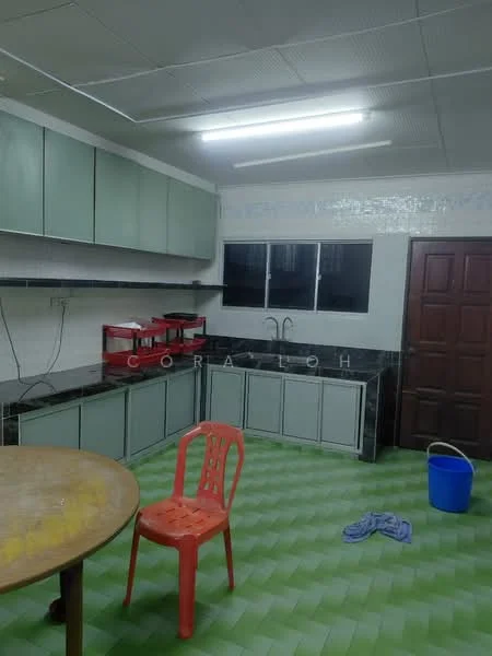 Kitchen features: green cabinetry, black countertop, double-bowl stainless-steel sink, chrome faucet, wall-mounted cabinets, tile backsplash, floor-to-ceiling windows, green and white checkered flooring, round dining table, plastic chair in orange, blue bucket, kitchen towel on the floor.