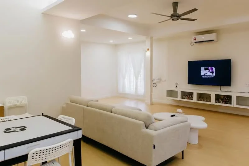 Living features: beige fabric sofa, coffee table, wall-mounted TV, entertainment unit, 5-blade ceiling fan, recessed downlights, white painted walls, light wood flooring, floor-to-ceiling windows with sheer curtains, air conditioning unit; style: modern. Dining features: dining table with black and white design, white plastic chairs; style: modern.