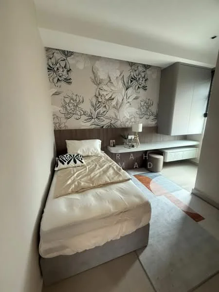 Bedroom features: single bed, upholstered headboard, decorative throw pillow, floral wallpaper, wood panel accent wall, nightstand with lamp, built-in wardrobe, desk with storage, area rug, neutral wall color, light-colored flooring; style: modern.