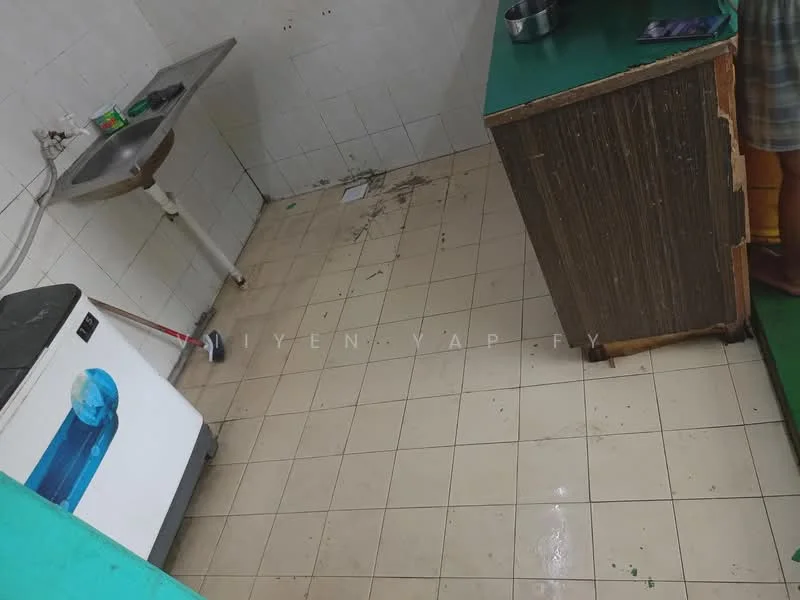 Kitchen features: white tiled walls, light-colored floor tiles, green countertop, single-bowl sink, built-in cabinet, washing machine, cleaning supplies, visible plumbing fixtures.