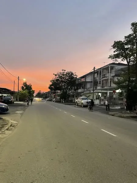 Exterior type: low-rise apartment block; features: two-storey building, balconies on upper floor, street view, paved road, streetlights, surrounding trees, residential area, vehicles parked along the street; style: modern.