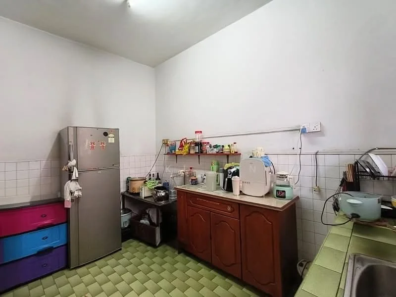 Kitchen features: stainless-steel fridge, wood cabinetry with brown finish, green tiled countertop, white tiled backsplash, sink with faucet, kitchen appliances including kettle and rice cooker, open shelving, colorful storage drawers in purple and blue, wall-mounted electrical outlets, fluorescent ceiling light.