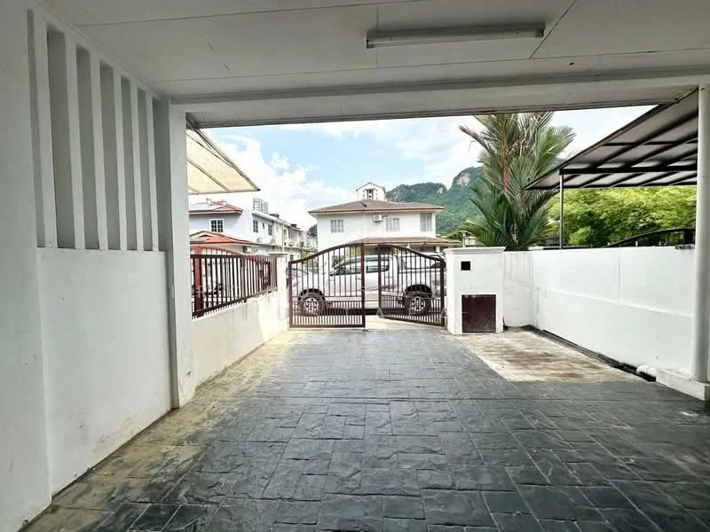 Exterior type: linked terrace house; features: paved driveway, metal gate, white painted walls, mountain view in background, surrounded by greenery, open-air parking area; style: modern.