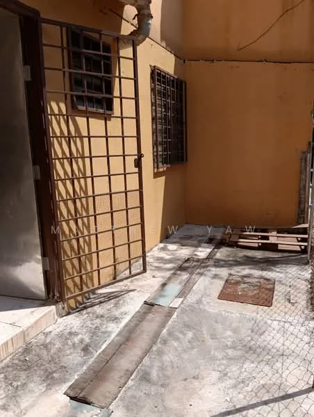 Exterior features: grilled security gate, yellow painted walls, concrete flooring, metal window grilles, exposed drainage pipe, fenced area, outdoor space, sliding door, walkway with tiles.