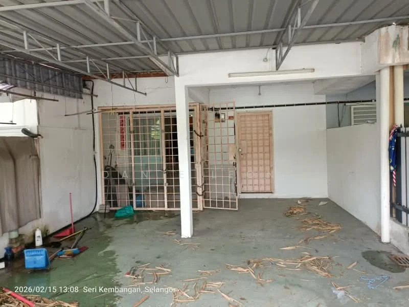 Room features: concrete flooring, white painted walls, metal roof, security grille door, exposed ceiling, cleaning tools visible, water hose, broom, debris on floor.