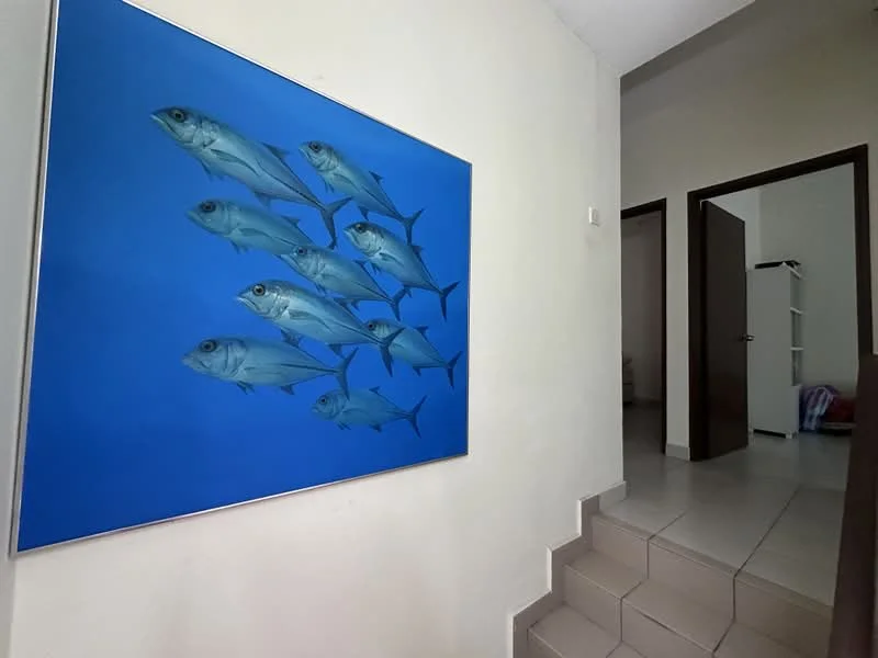 Room features: painted walls in light color, tile flooring, staircase leading up, framed artwork of fish, doorway leading to another room, open space, natural light from nearby window; style: modern.