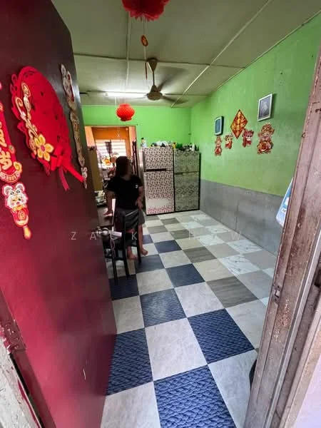 Room features: green painted walls, grey painted lower wall, ceiling fan, checkered tile flooring in blue and white, decorative wall hangings, wooden door, plastic storage boxes, table with chairs.