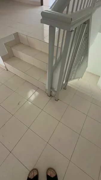 Room features: white tiled flooring, staircase with grey railing, neutral wall colour, natural light from nearby window, clean and uncluttered space, no visible furniture or decor; style: modern.