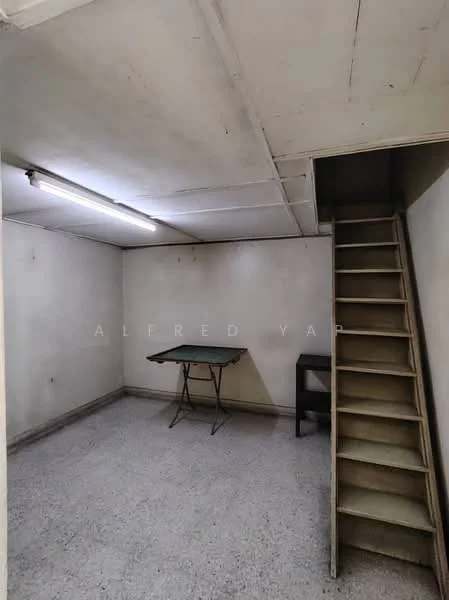 Room features: plain white walls, concrete flooring, fluorescent ceiling lights, staircase leading to upper level, folding table, small black table, unfinished ceiling, no visible windows; style: minimalist.