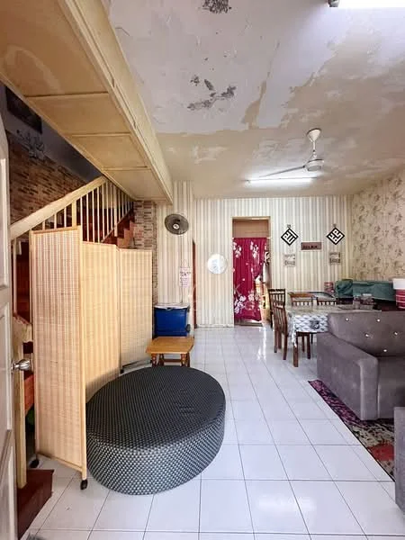 Living features: white tiled flooring, exposed brick accent wall, cream wallpaper with floral pattern, ceiling fan, wooden dining table with chairs, grey fabric sofa, round ottoman, decorative area rug, partition screen, staircase with wooden railing, wall-mounted fan; style: traditional.