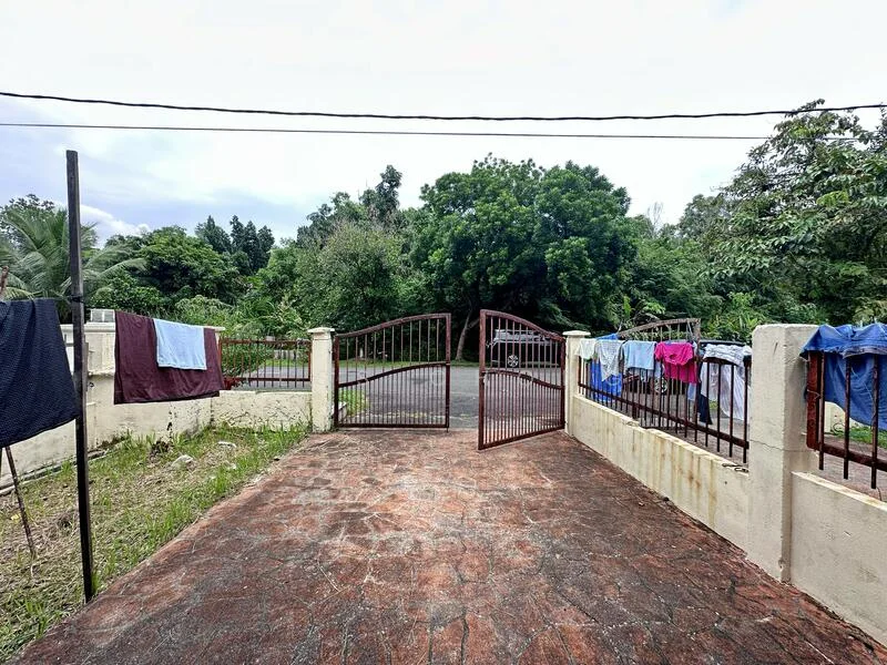 Exterior features: gated entrance, stone-paved driveway, fenced perimeter, laundry hanging on fence, manicured lawn, surrounded by greenery, two gates, concrete wall.