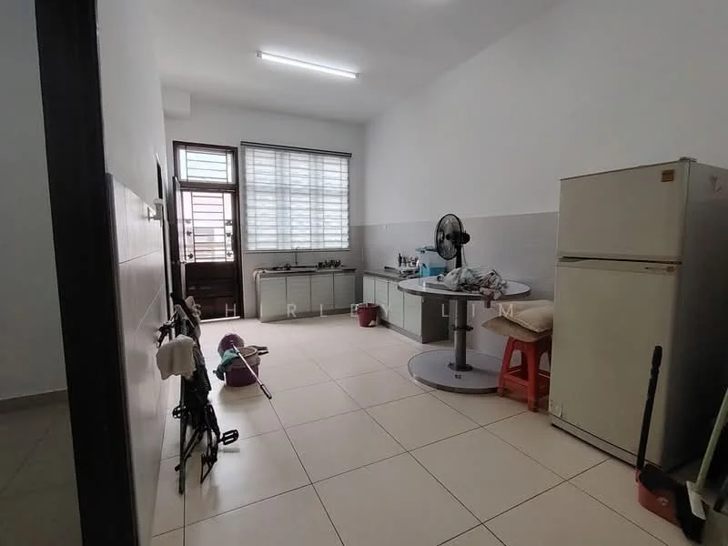 Room features: white painted walls, tile flooring, large window with blinds, ceiling light fixture, round dining table, red plastic chair, stainless-steel fridge, fan, kitchen counter, cleaning supplies, broom, mop, bicycle, plastic storage container.