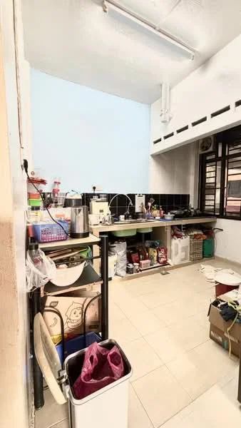 Kitchen features: black tiled backsplash, white walls, light grey ceiling, laminate countertop, stainless-steel sink, chrome faucet, open shelving, kitchen cabinets, floor tiles, various kitchen appliances, trash bin, multiple storage containers.