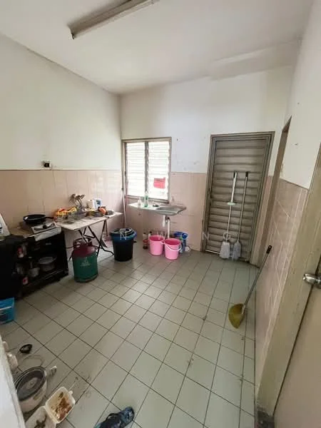 Laundry features: white painted walls, light grey tiled flooring, single-bowl stainless-steel sink, chrome faucet, window with horizontal slats, wooden door, plastic storage bins in pink, plastic storage bins in green, cleaning tools visible, folding table, various kitchen appliances, broom.
