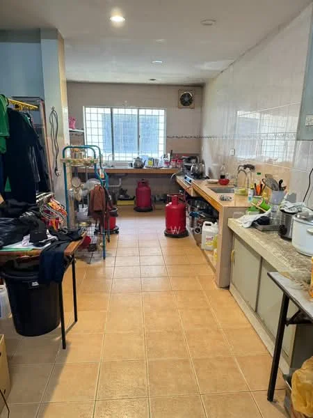 Kitchen features: tile flooring, light grey walls, window with grid pattern, stainless-steel sink, wooden countertop, kitchen cabinets, multiple gas canisters, various kitchen appliances, cleaning supplies, open shelving, clothes drying rack, broom and mop, storage boxes, utility cart.