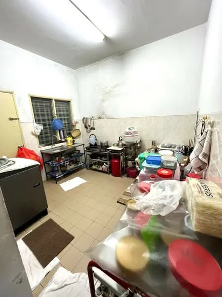 Kitchen features: white painted walls, tile flooring, single-bowl stainless-steel sink, chrome pull-down faucet, stainless-steel countertop, wooden shelving unit, metal storage racks, various kitchen appliances, window with security bars, overhead fluorescent lighting, floor mat, plastic storage containers.