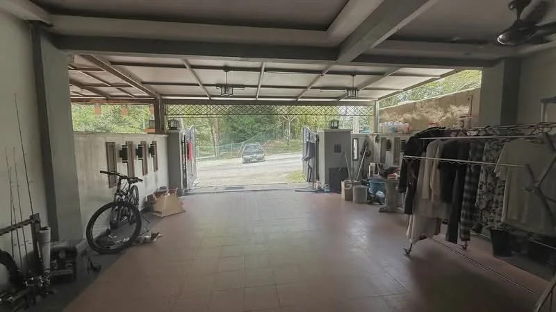 Exterior type: car porch; features: open-air parking space, tiled flooring, metal gate, two ceiling fans, bicycle, clothes rack with hanging clothes, storage shelves, visible driveway, surrounded by greenery; style: modern.