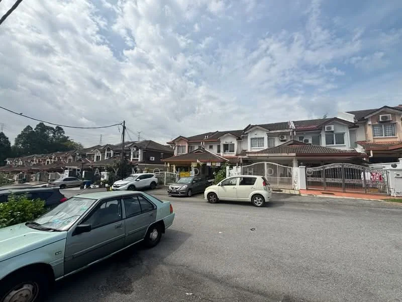 Exterior type: linked terrace house; features: two-storey linked terrace houses, cream painted facade, red tiled roof, front porch with gate, manicured lawn, driveway with interlocking pavers, visible cars parked on the street, surrounded by greenery, urban residential setting, cloudy sky; style: modern.