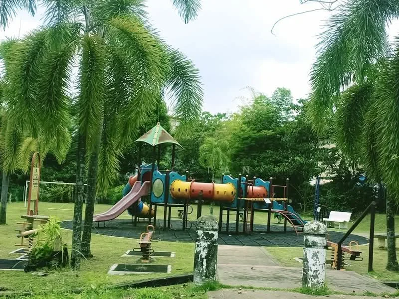 Exterior type: landscape garden; features: children's playground with slides and climbing structures, manicured lawn, palm trees, wooden benches, playground safety flooring, surrounding greenery, pathway leading to playground, decorative stone pillars at entrance; style: tropical-modern.