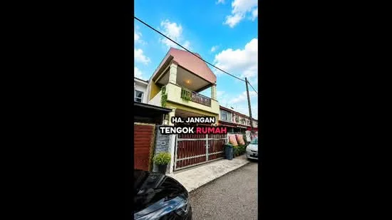 Exterior type: linked terrace house; features: two-storey building, cream painted facade, red accent roof, balcony with railing, manicured front yard, driveway with interlocking pavers, visible car parked in driveway, surrounded by residential area; style: modern.