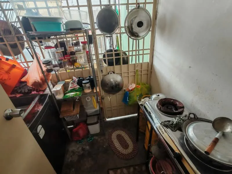 Room features: metal shelving units, various cooking pots and pans, plastic storage containers, wooden countertop, floor mat with oval pattern, refrigerator, hanging storage bags, concrete flooring, wall with window, open space layout; style: functional.
