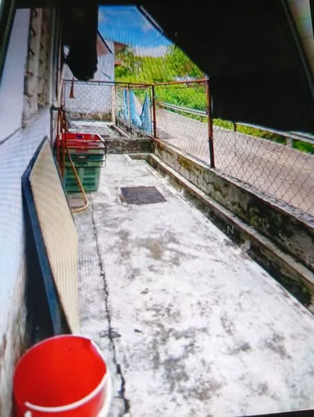 Room features: concrete flooring, fenced area, green plastic storage bins, red plastic bucket, drainage channel, exposed wall, outdoor space, partial roof cover.