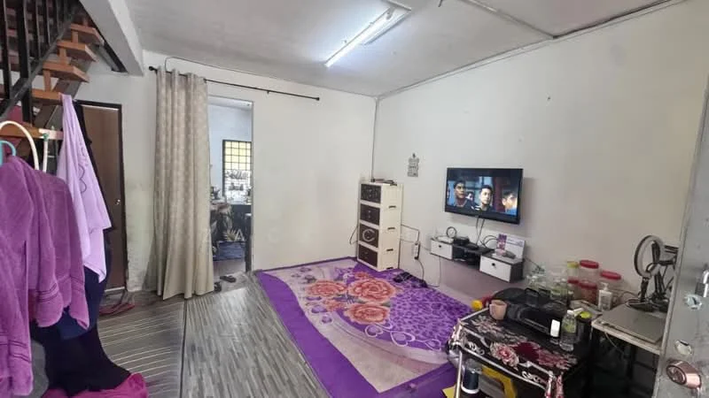 Living features: grey laminate flooring, white painted walls, recessed ceiling lights, wall-mounted TV, TV console, area rug with floral pattern, black coffee table, decorative table with plants, curtains, staircase visible in background, clothes hanging rack.