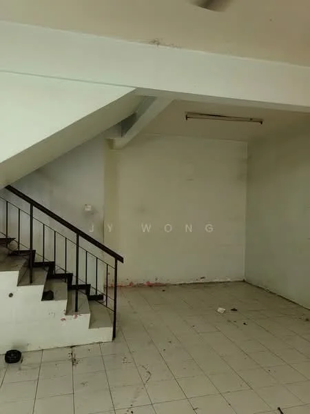 Room features: white painted walls, tile flooring, staircase with metal railing, ceiling light fixture, empty space, no visible furniture, corner with wall stains, open layout.