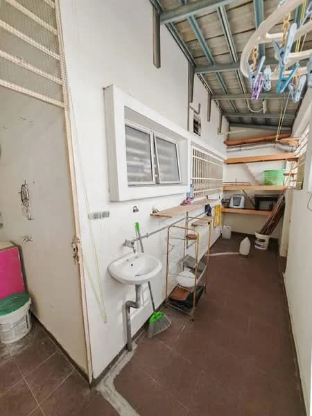 Laundry features: white painted walls, brown tiled flooring, single-bowl sink, metal shelving unit, washing machine, clothes drying rack, window with horizontal slats, utility storage area, broom, cleaning supplies, bucket.